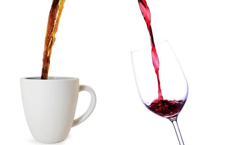Two liquids being poured side-by-side: a dark beverage (coffee) into a white mug, and a red beverage (wine) into a wine glass.